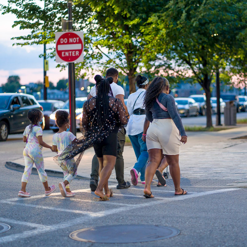 Image of a family crossing the street using a crosswalk.