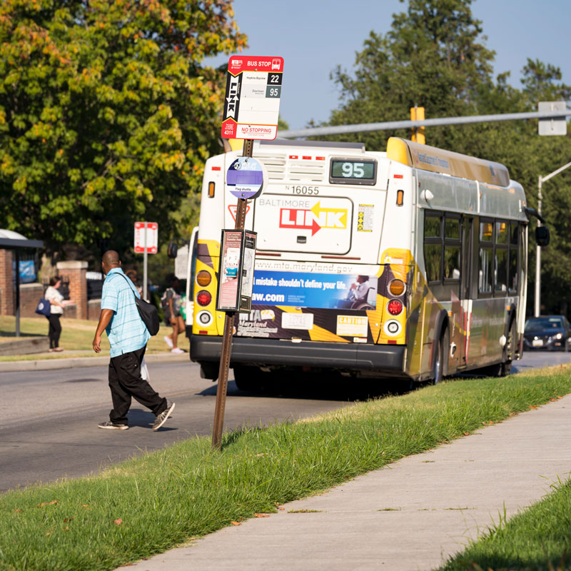 Image of a man crossing the street behind an MTA bus.